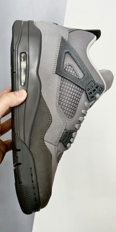 A high-quality grayscale sneaker held in hand, showcasing modern design details.