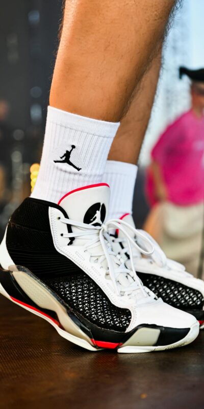 Close-up of trendy black and white sneakers with visible logo during an outdoor event.