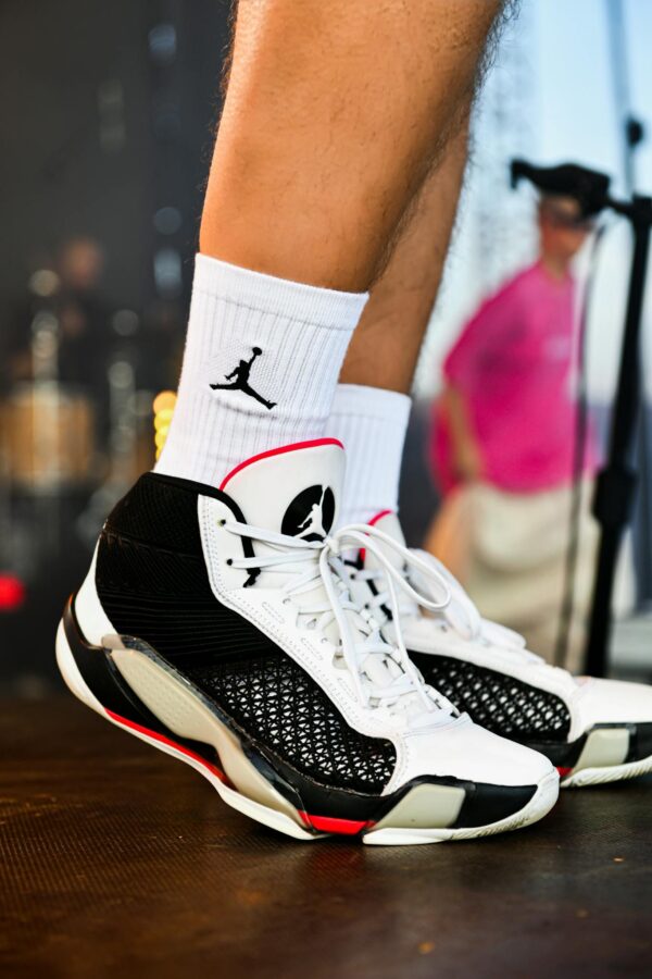Close-up of trendy black and white sneakers with visible logo during an outdoor event.